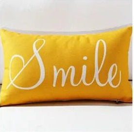 Rectangular mustard cushion cover with white Smile lettering.