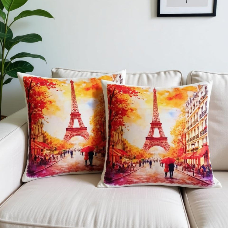 Two cushion covers with red and orange autumn scenes around the Eiffel Tower on a sofa.