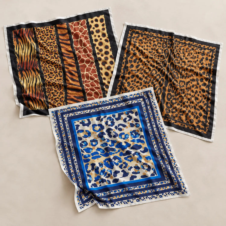 Three square patterned scarves laid flat on a light beige background. One scarf features vertical stripes with tiger, leopard, and giraffe prints in orange, brown, and black.