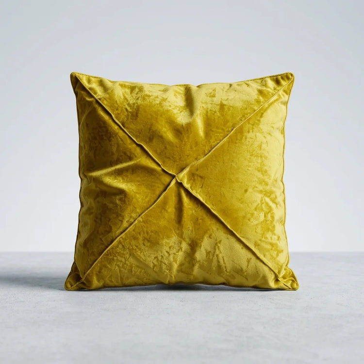 A square yellow velvet throw pillow with a crisscross stitched design on a light gray background.