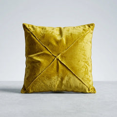 A square yellow velvet throw pillow with a crisscross stitched design on a light gray background.