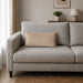Plain rectangular cream filled cushion on a pale sofa.