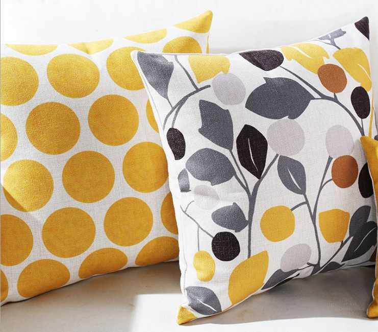 Close view of yellow dot and grey botanical cushion covers on a sofa.