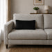 Plain rectangular black filled cushion on a pale sofa.