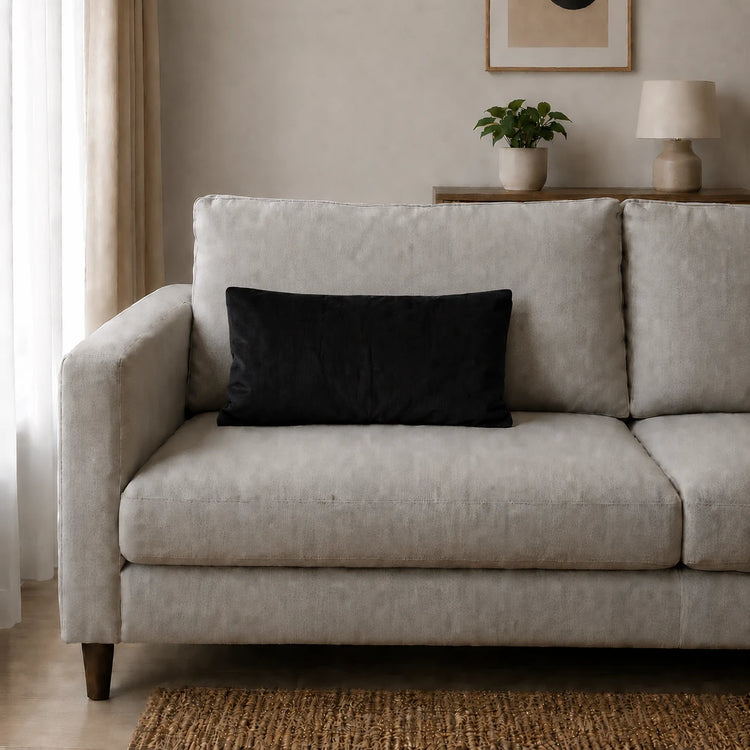 Plain rectangular black filled cushion on a pale sofa.