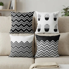 Four decorative throw pillows arranged on a beige sofa. The designs include black and white chevron patterns and black cactus illustrations on white backgrounds.