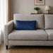 Plain rectangular blue filled cushion on a pale sofa.