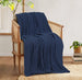 Navy cotton thermal blanket draped over a wooden armchair.