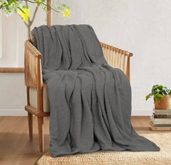 Charcoal grey cotton thermal blanket draped over a wooden armchair.