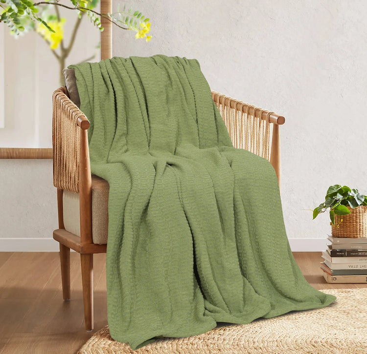 Olive green cotton thermal blanket draped over a wooden armchair.