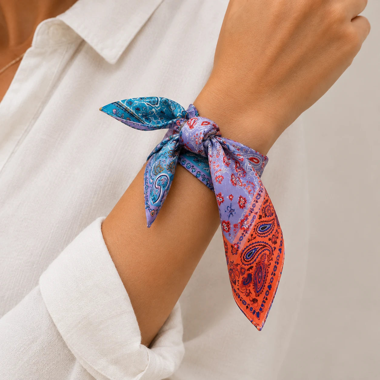 A close-up of a person's wrist wearing a bandana tie, styled with a white collared shirt.