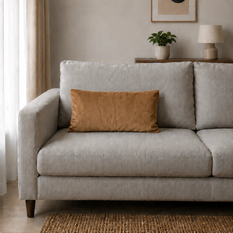 Plain rectangular tan filled cushion on a pale sofa.