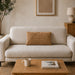Rectangular tan filled cushion with angular stitched lines on a cream sofa.