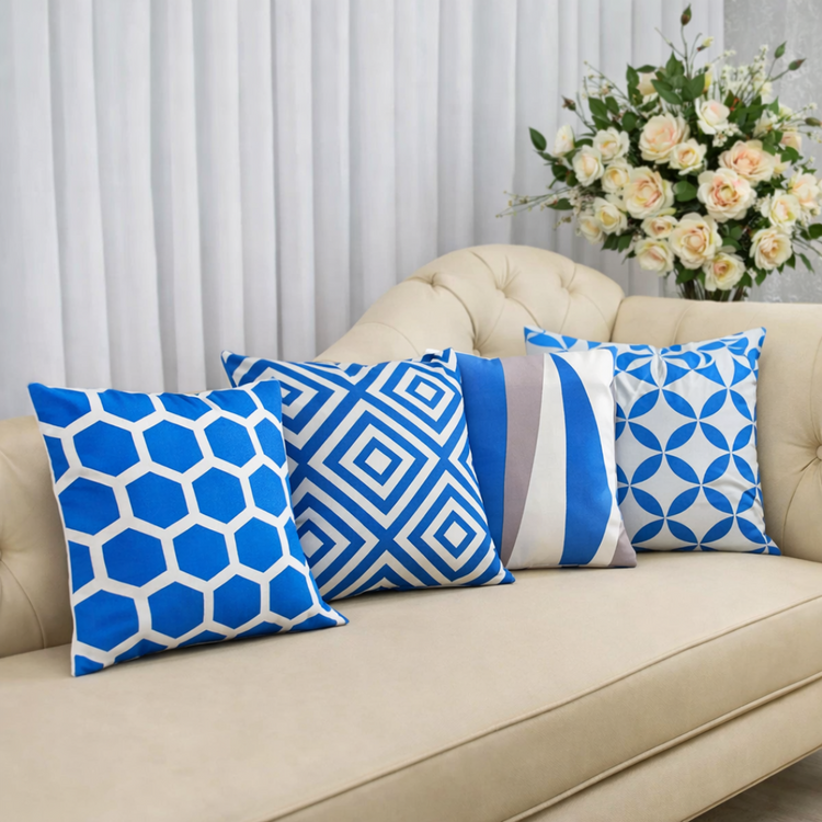 Blue and white geometric cushion covers arranged on a cream sofa.