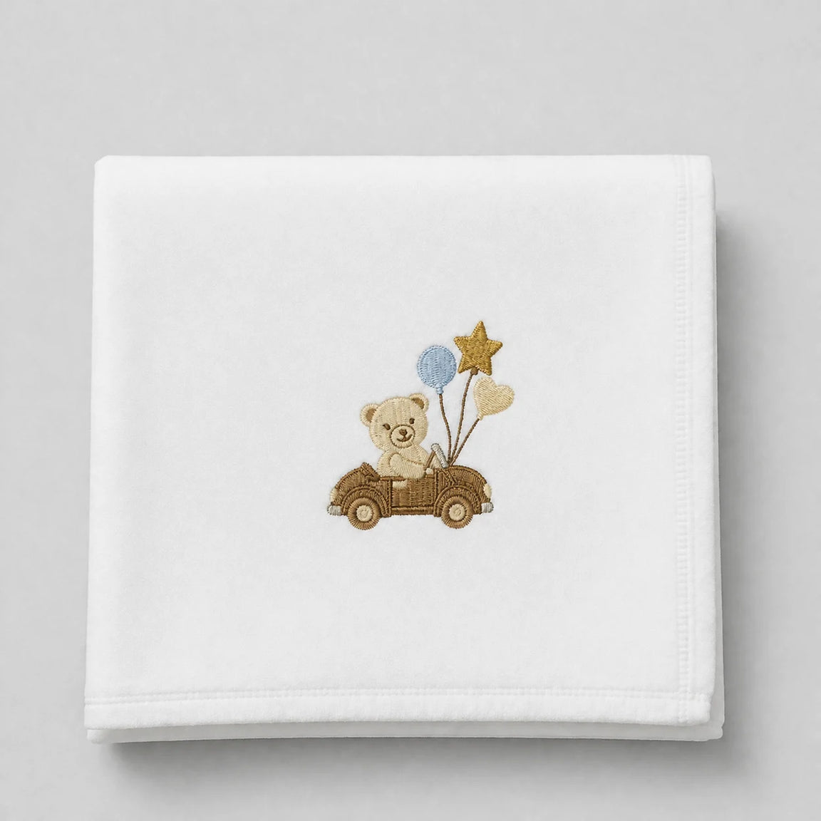 White blanket folded flat with a teddy bear in a car and balloons