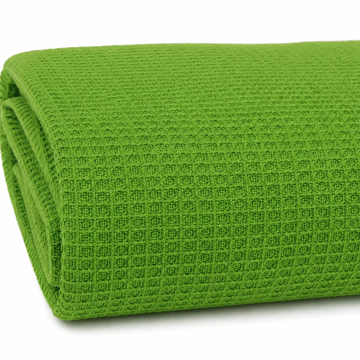 Close-up of the folded edge and texture of a bright green waffle-weave blanket.