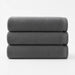 Three folded charcoal cotton bath towels stacked together.