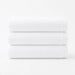 Three folded white cotton bath towels stacked together.