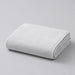 Folded white bath towel on a light grey surface.