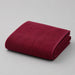 Folded burgundy bath towel on a light grey surface.