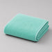 Folded mint bath towel on a light grey surface.