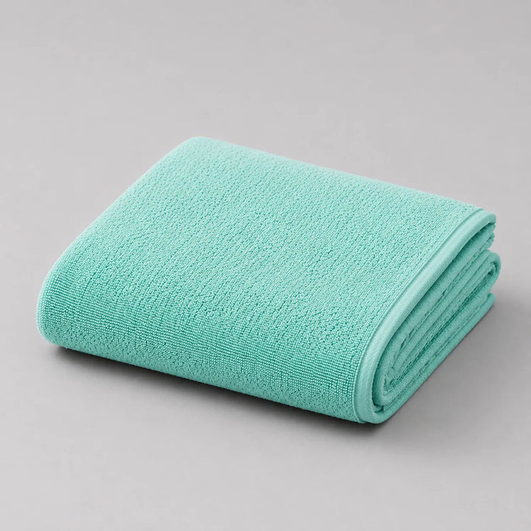Folded mint bath towel on a light grey surface.
