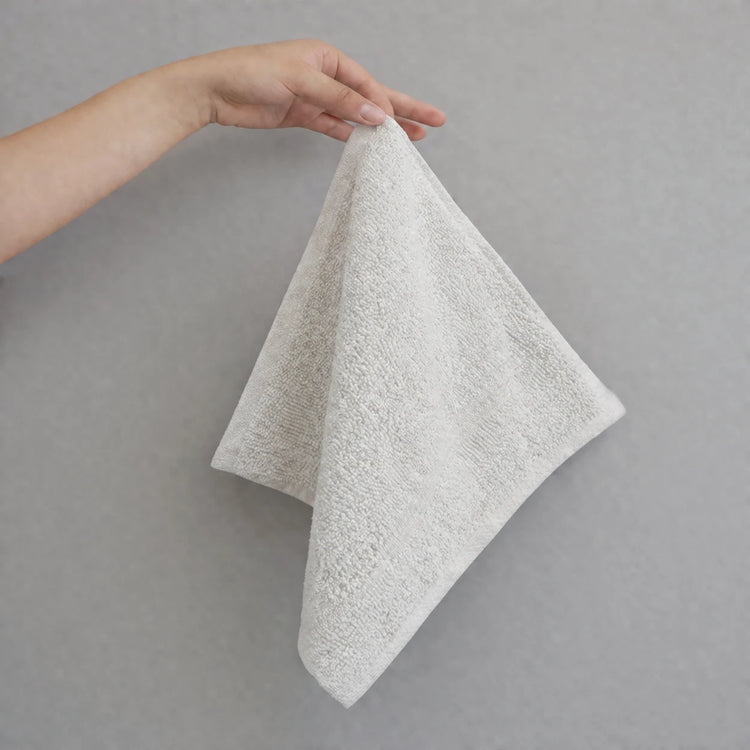 Cream hand towel held up by one corner.