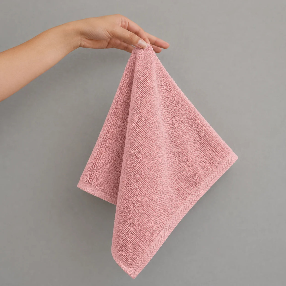 Dusty pink hand towel held up by one corner.