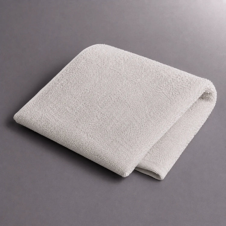 Folded cream hand towel on a grey surface.