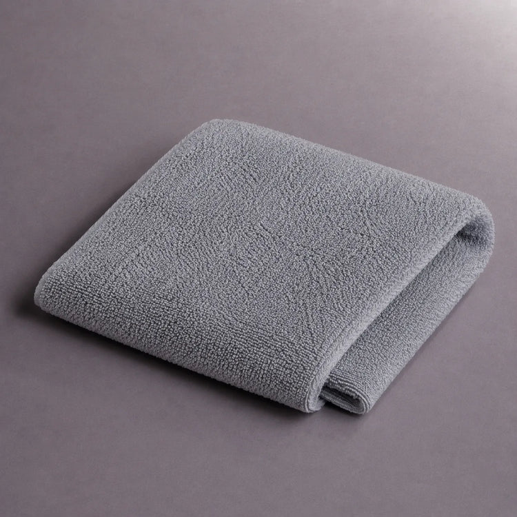 Folded grey hand towel on a grey surface.