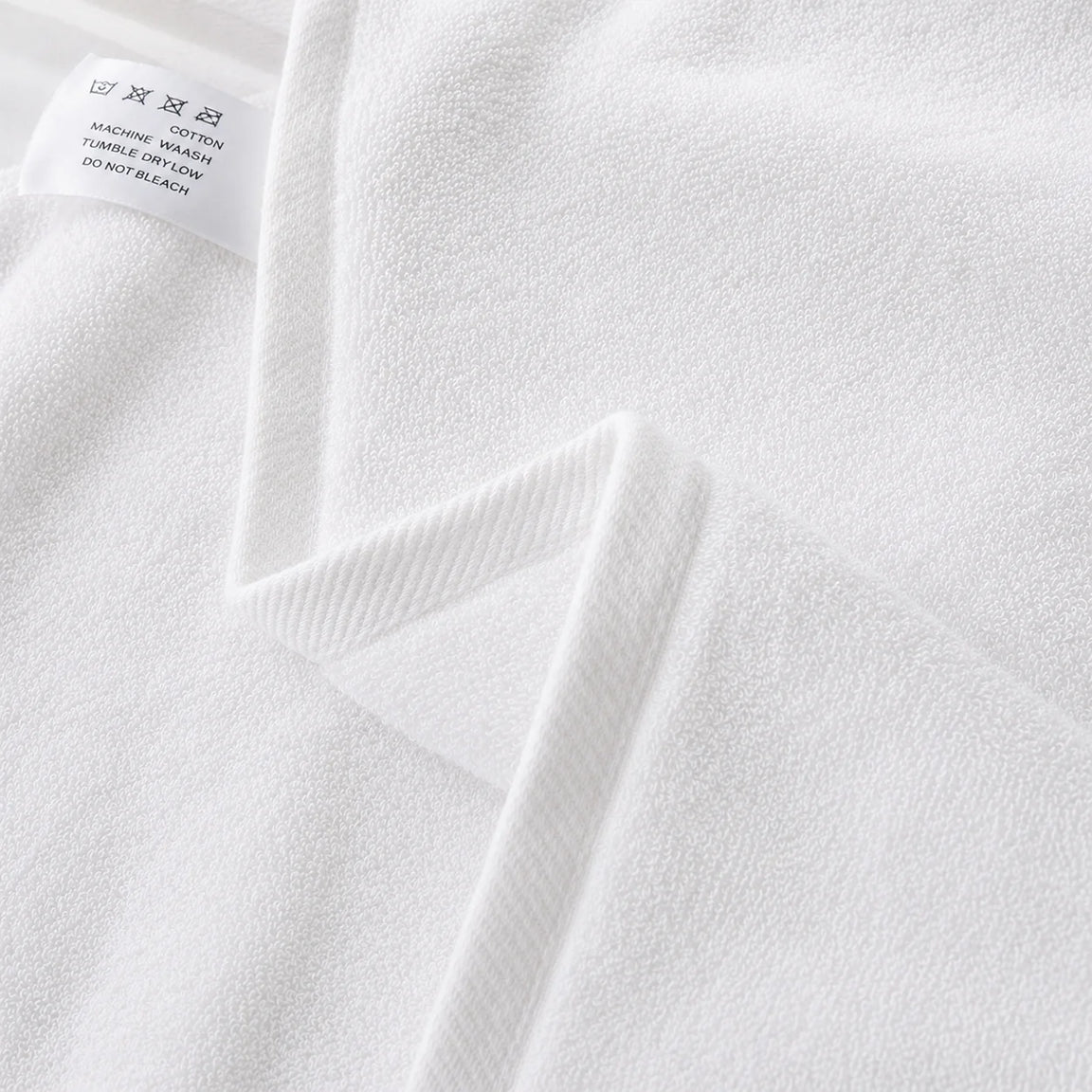 Close-up of the hem and texture of a white cotton bath towel.