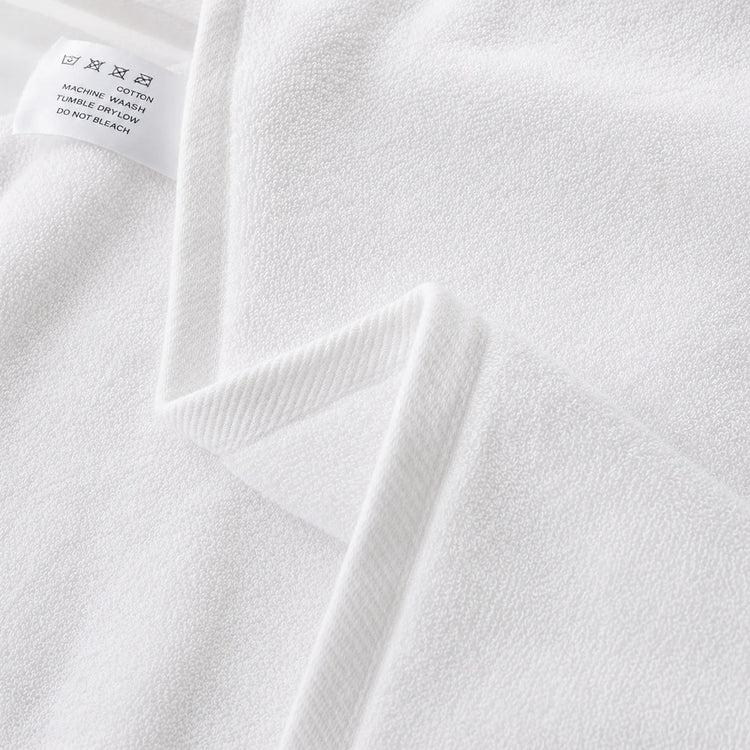 Close-up of the hem and texture of a white cotton bath towel.