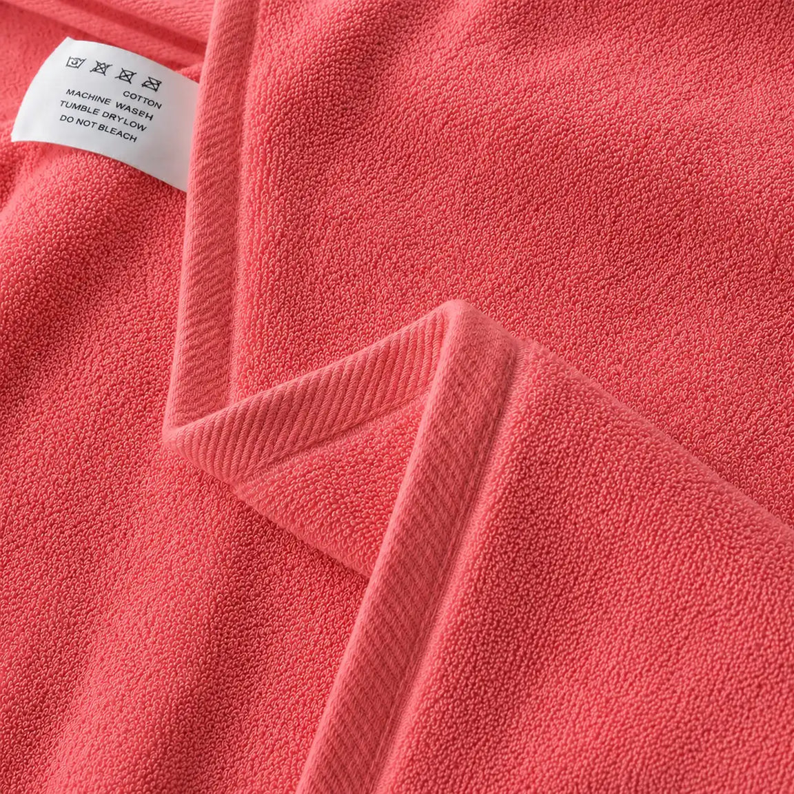 Close-up of the hem and texture of a coral cotton bath towel.