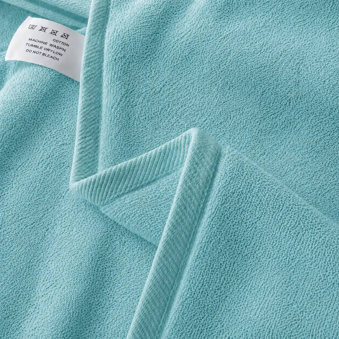 Close-up of the hem and texture of a turquoise cotton bath towel.