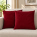Two burgundy cushion covers with diagonal stitched lines on a cream sofa.