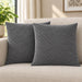 Two silver grey cushion covers with diagonal stitched lines on a cream sofa.