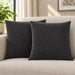 Two charcoal grey cushion covers with diagonal stitched lines on a cream sofa.