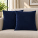 Two navy cushion covers with diagonal stitched lines on a cream sofa.