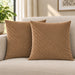 Two tan cushion covers with diagonal stitched lines on a cream sofa.