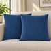 Two blue cushion covers with diagonal stitched lines on a cream sofa.