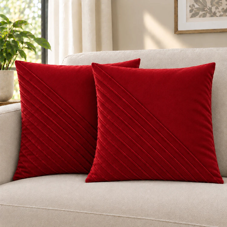 Two red cushion covers with diagonal stitched lines on a cream sofa.