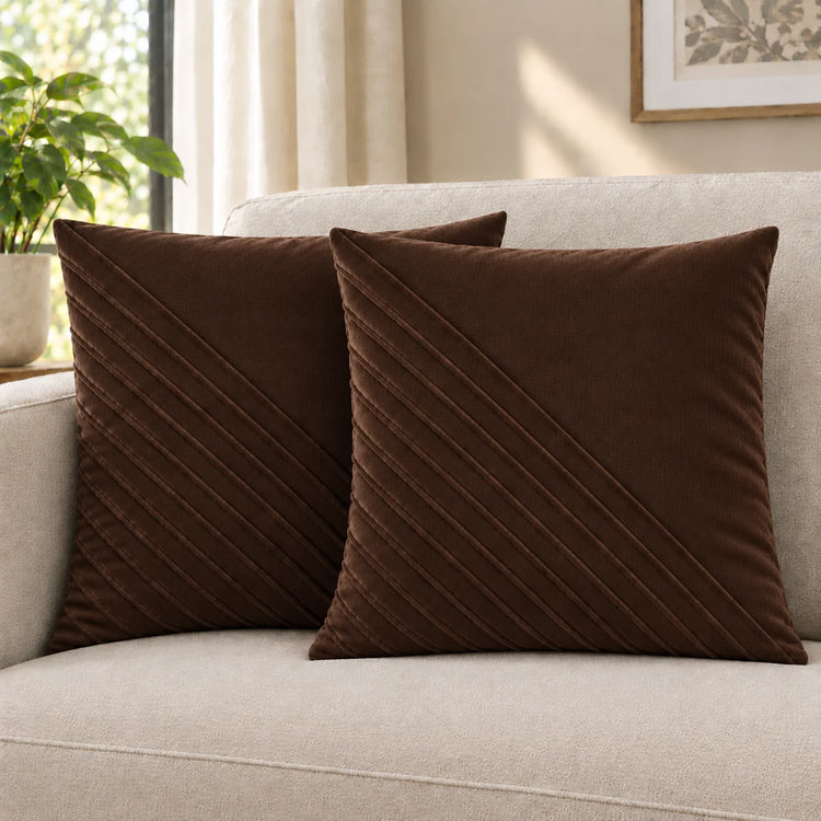Two brown cushion covers with diagonal stitched lines on a cream sofa.