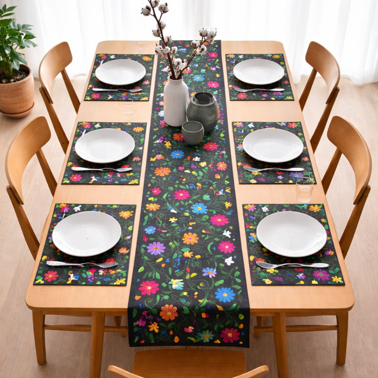 Black table runner with bright floral motifs and matching placemats on a dining table.