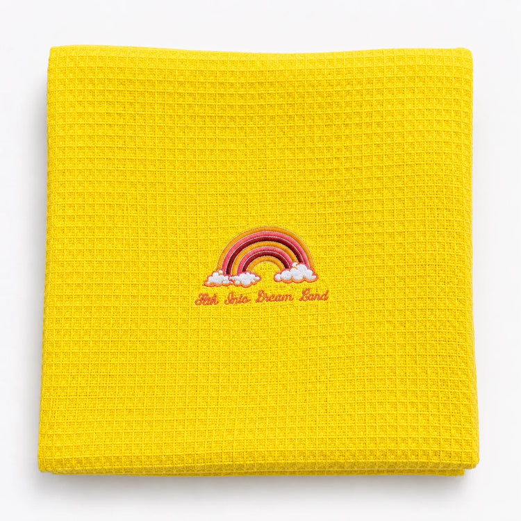 Folded bright yellow waffle-weave baby blanket with a rainbow motif.