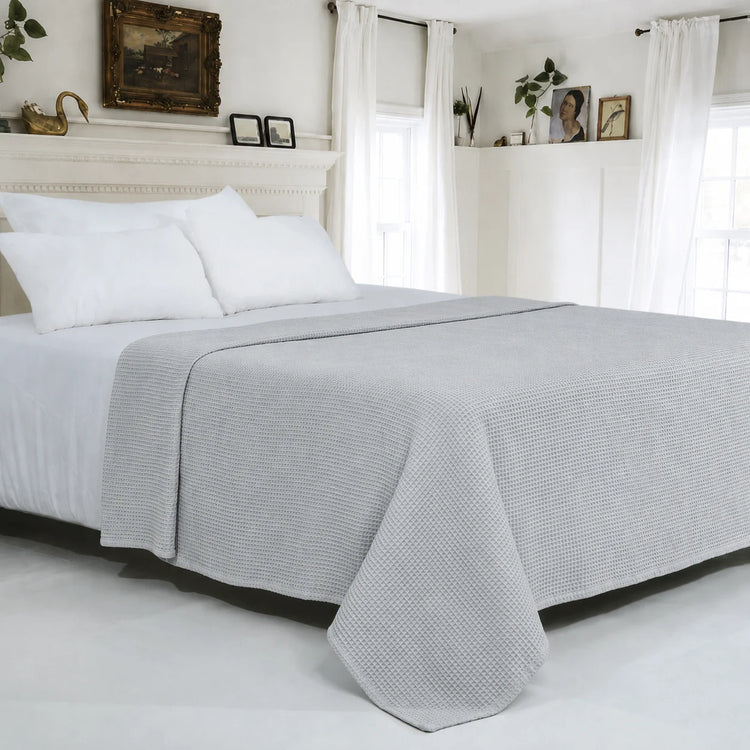 Light grey textured cotton thermal blanket spread across a bed.