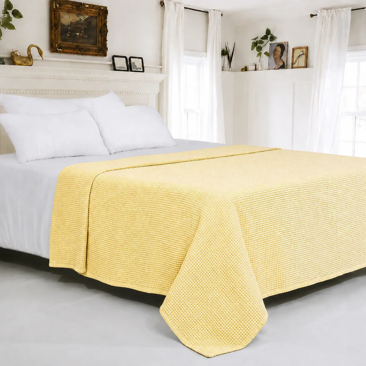 Pale yellow textured cotton thermal blanket spread across a bed.