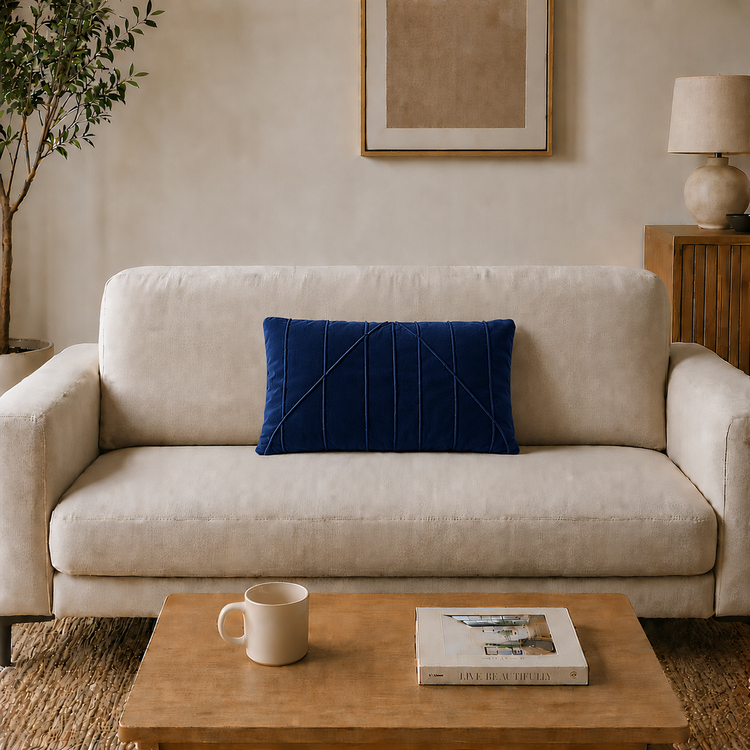 Rectangular navy filled cushion with angular stitched lines on a cream sofa.