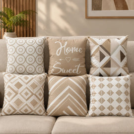 Six beige and cream cushion covers with geometric patterns and Home Sweet lettering.