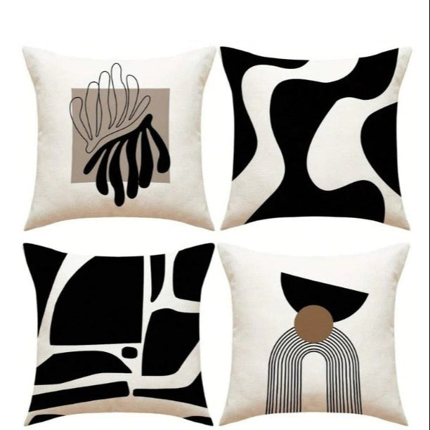 Four black and cream cushion covers with bold abstract shapes and botanical line art.