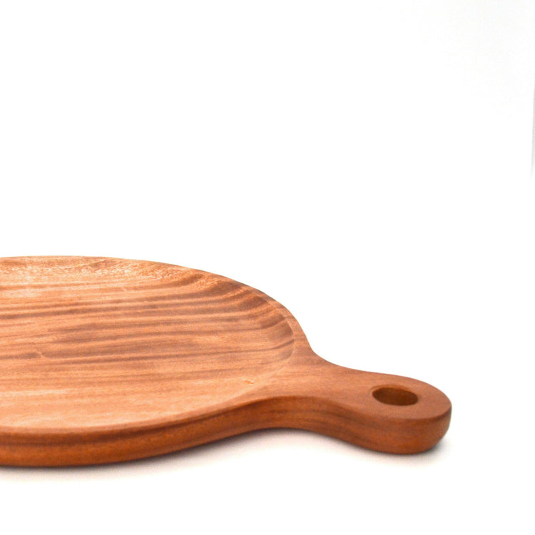 Close-up of a wooden pizza board's handle, hanging hole and wood grain.